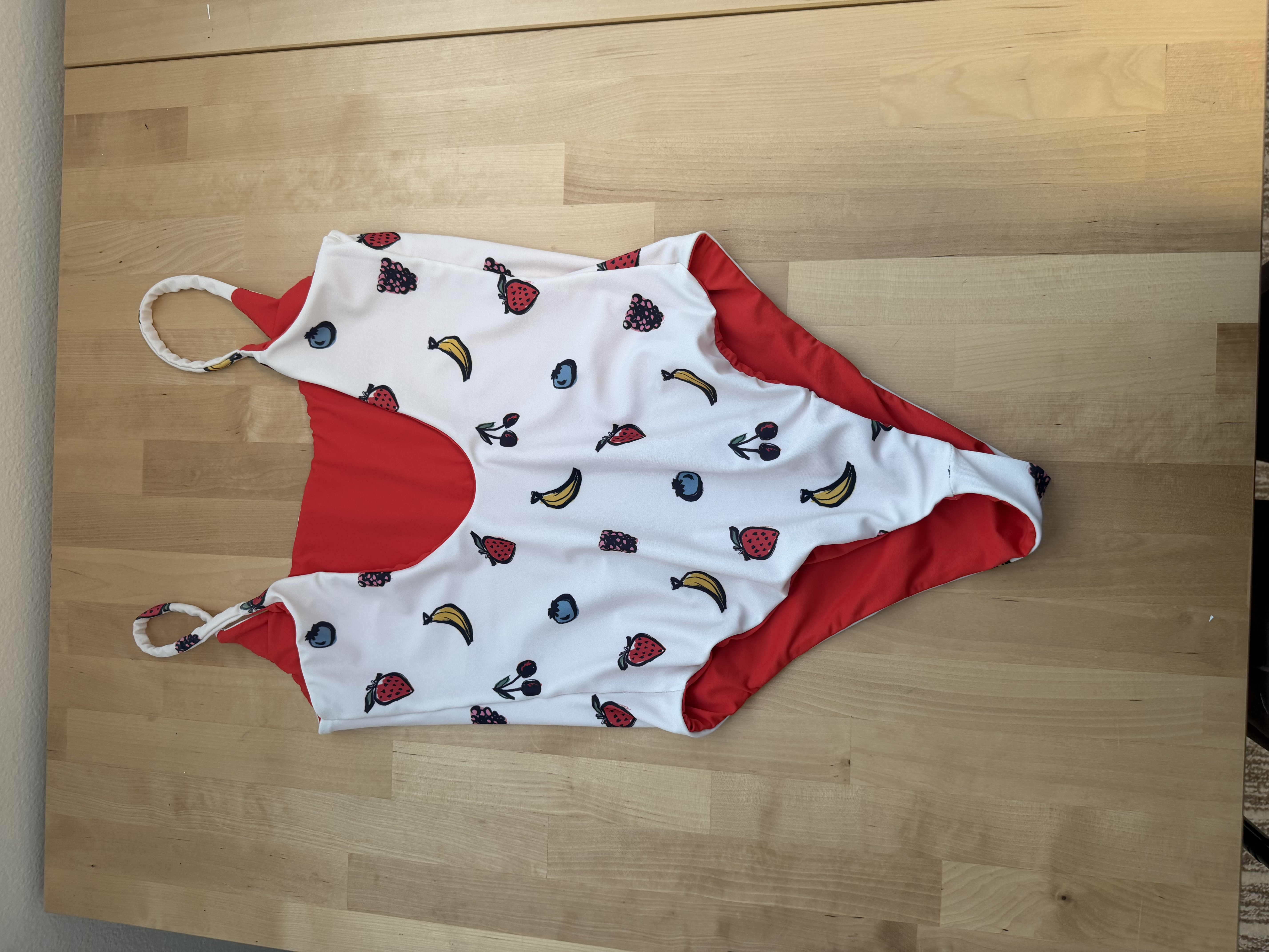 The finished Olivia One Piece swimsuit folded open showing the red lining fabric inside